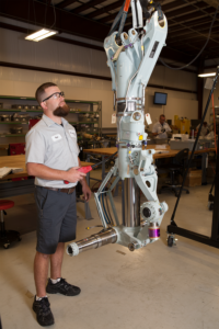 A uniformed Professional Aircraft Accessories technician works on CRJ 700-900 landing gear as part of an exclusive landing gear overhaul agreement with PSA Airlines. 
